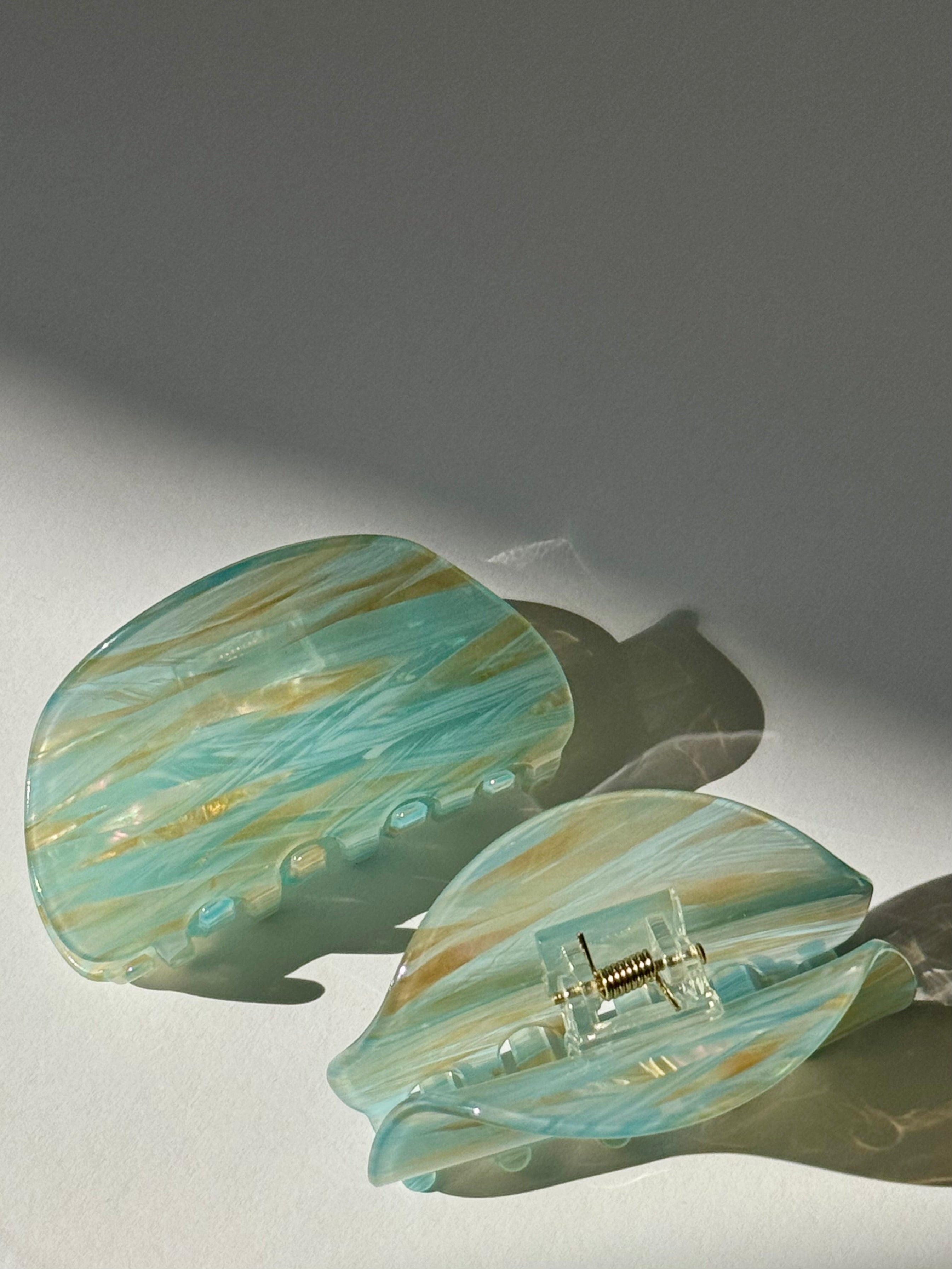 Turquoise and gold marbled hair clip on a light gray background